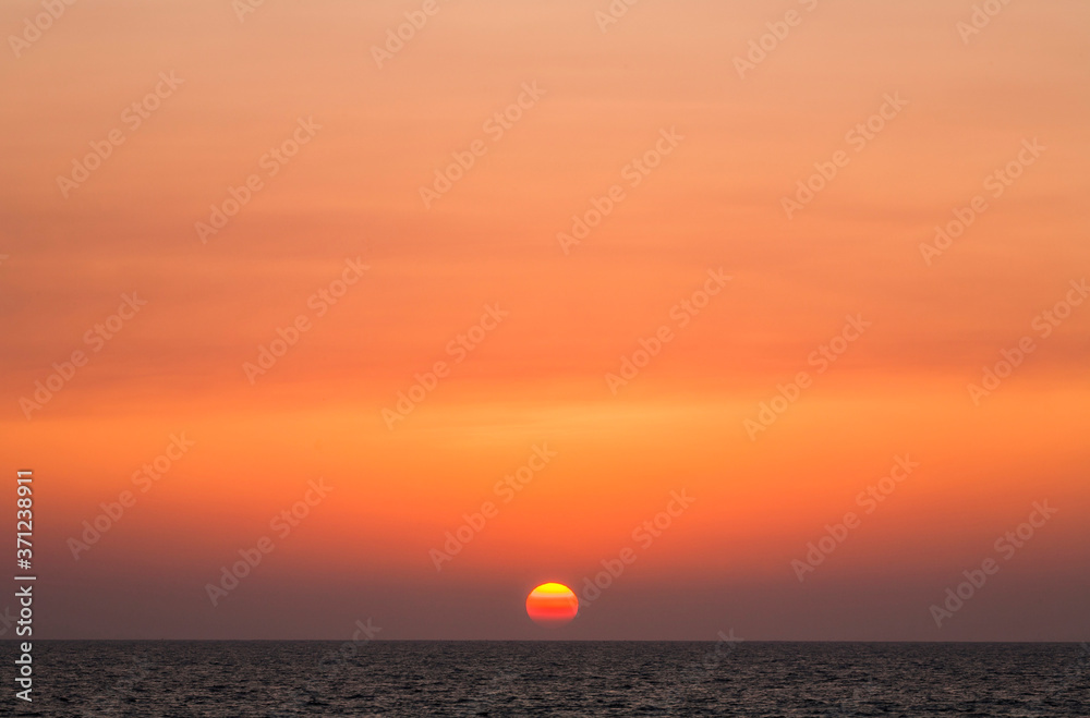Brilliant orange-red clouds reflected into the ocean in a beautiful sunset
