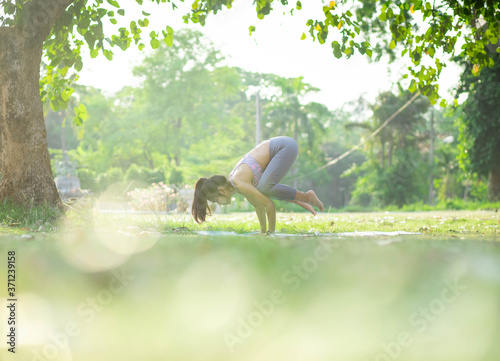 Young asian woman doing yoga under the tree in park © Near