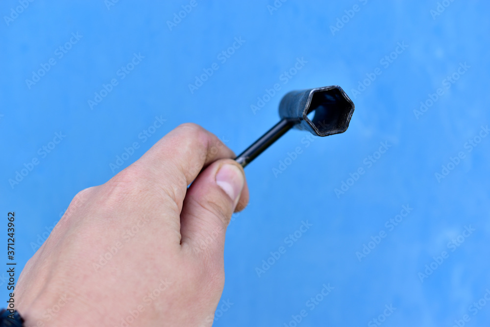 Iron candle key with a screwdriver in hand on a blue background Iron candle key with a screwdriver in hand on a blue background