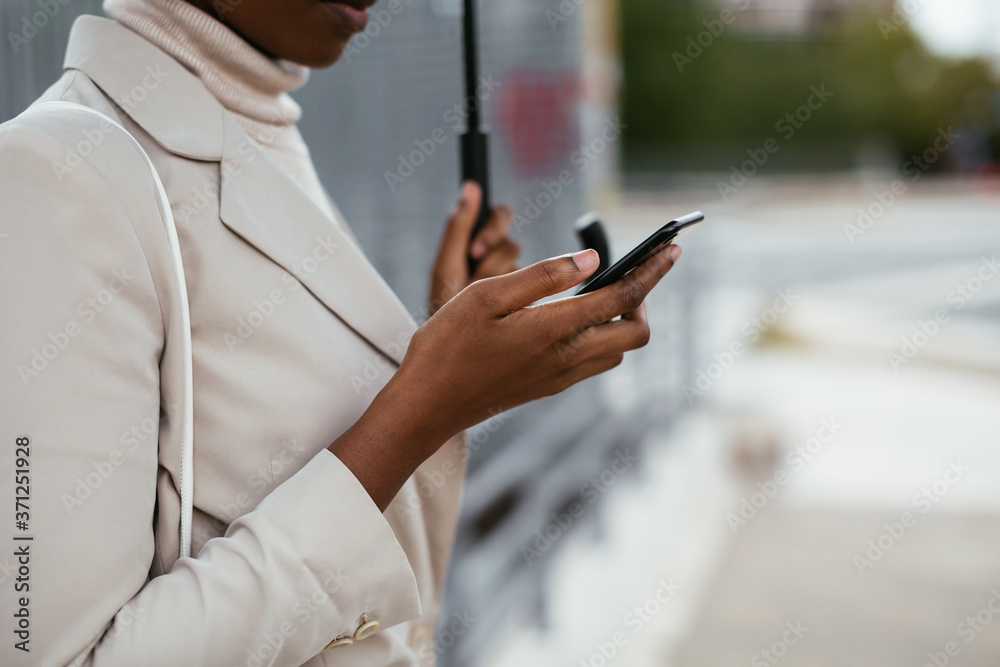 Crop black female using smartphone under umbrella Crop black female using smartphone under umbrella