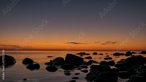 orange sunset by the sea, black stone silhouettes against the sea background, summer © ANDA