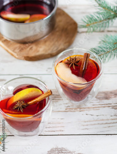 Christmas mulled red wine with spices and fruits over Christmas decorated background.