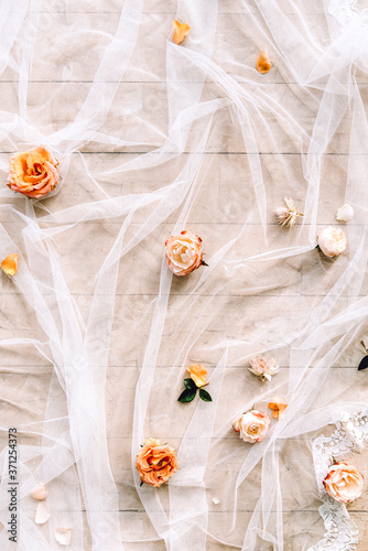 flat lay with roses and white chiffon fabric on wooden floor background