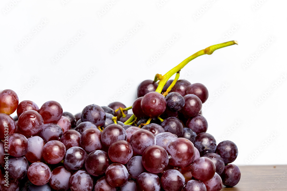 Close-up of red seedless grapes with water droplets on a white background.