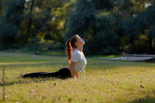 Redhead woman warming up before practicing yoga in the nature. photo