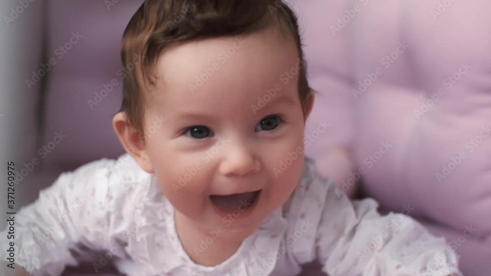 Newborn baby, Care and Love, Portrait of a Child. A small child lies on his stomach in the crib and laughs. Newborn baby, Care and Love, Portrait of a Child. A small child lies on his stomach in the crib and laughs.