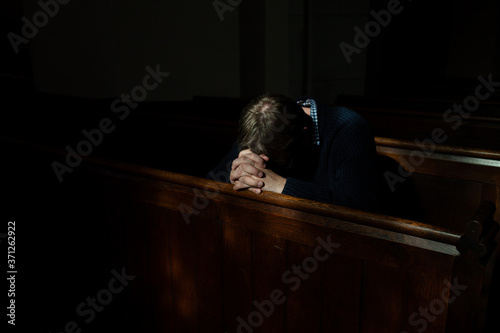Man bows his head in prayer in Church.