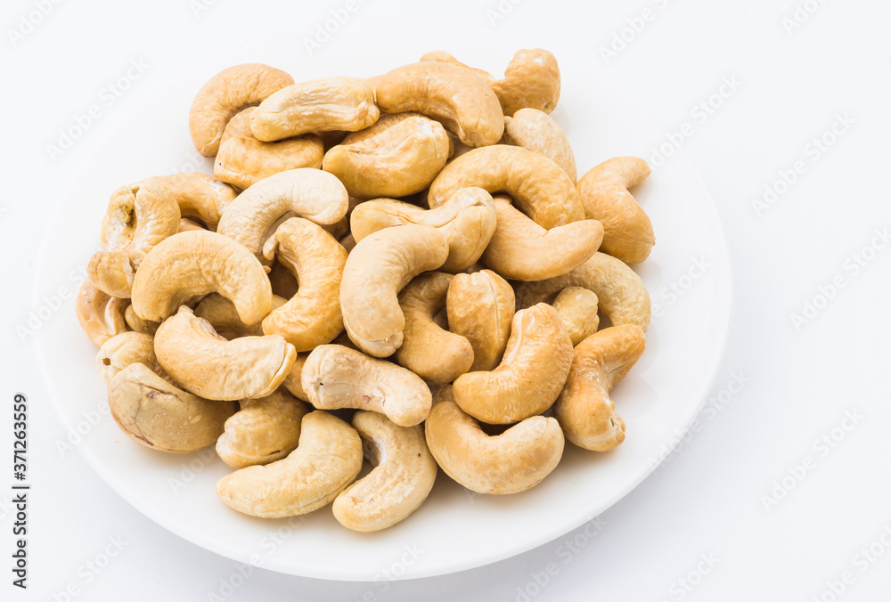 fresh cashew nuts on a white dish above the white background fresh cashew nuts on a white dish above the white background