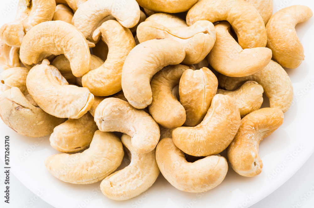 fresh cashew nuts on a white dish above the white background fresh cashew nuts on a white dish above the white background