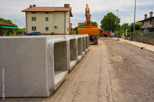 Reinforced concrete box culverts. These square pre-cast culverts are part of a sewage replacement scheme in NW Italy. In the background there is a crawler excavator with a rotating house platform