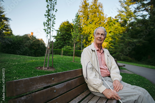 Visually impaired older man sitting on bench in nature