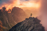 Man in mountains, silhouette of young hiker, sunset sky and hills in background Travel, adventure or expedition concept..
