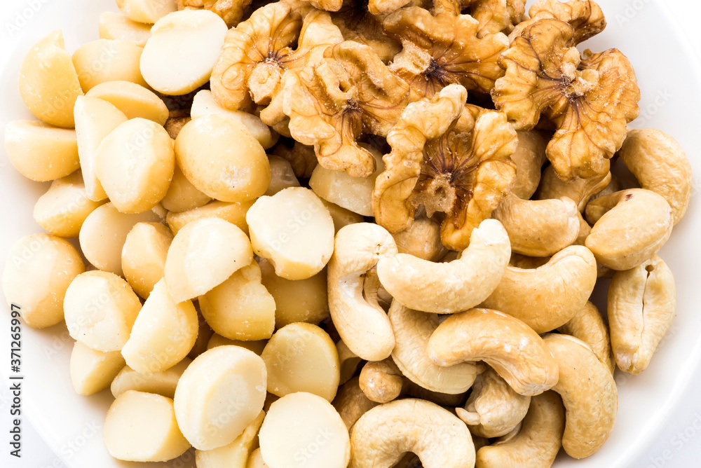 Variety of fresh nuts on a white dish above the white background Variety of fresh nuts on a white dish above the white background