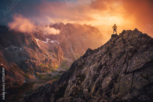 Hiker on the top of the hill looking at beautiful sunset sky. Silhouette of young hiker, edit space. Travel, adventure or expedition concept.