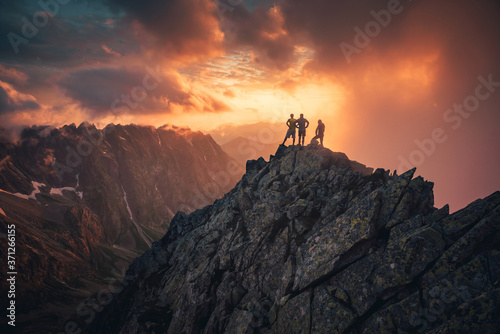 Group of people on mountain top against sunset lakes and mountains. Travel, adventure or expedition concept.. photo