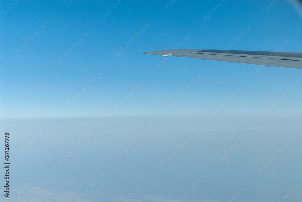 飛行機の機内から見た主翼と青空