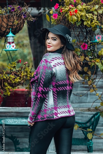 Beautiful model posing for photos on the street. Wearing black pants, purple blouse and hat. 