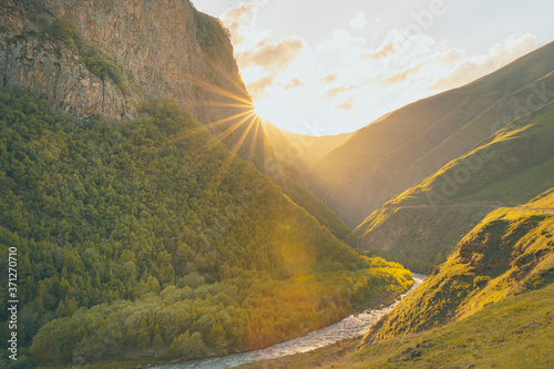 Road and the river surounded by picturesque mountains and setting suns flare. Dramatic landscapes of Georgia. photo