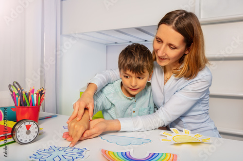 Boy with autism learn weather using cards, teacher hold hands and point to correct one photo