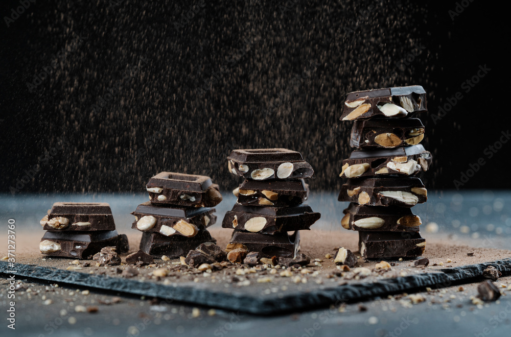 pieces of chocolate with almonds on black background