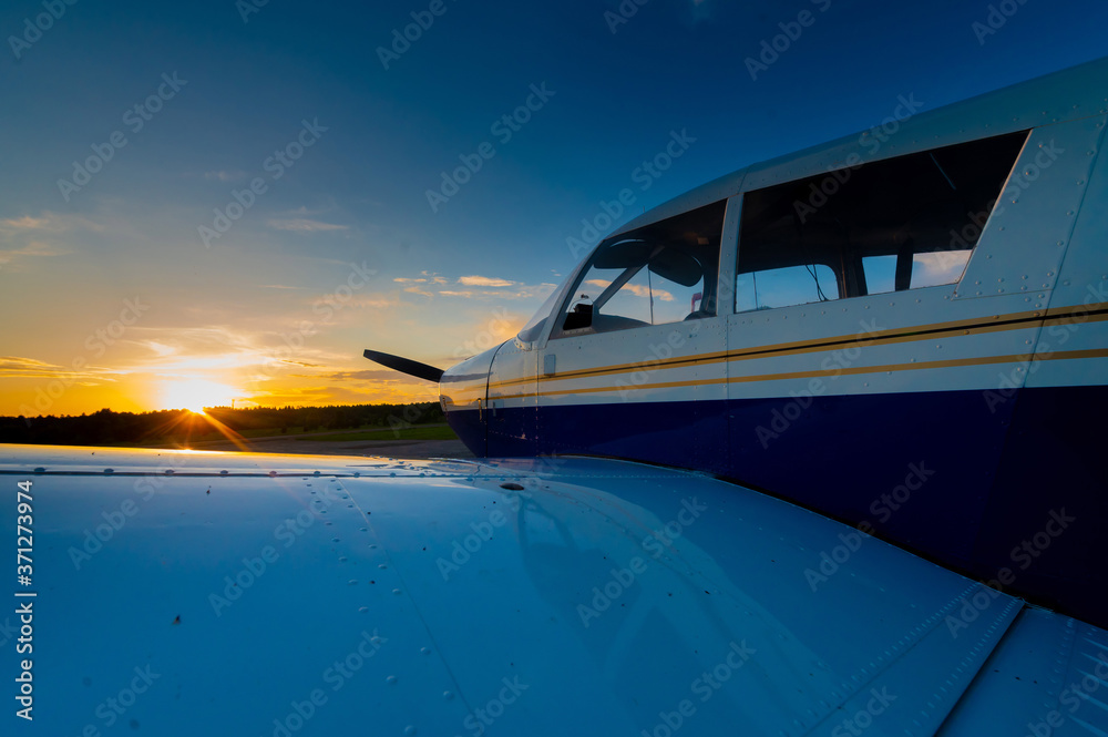Close-up of a small parked plane with a propeller against the backdrop of a sunset.