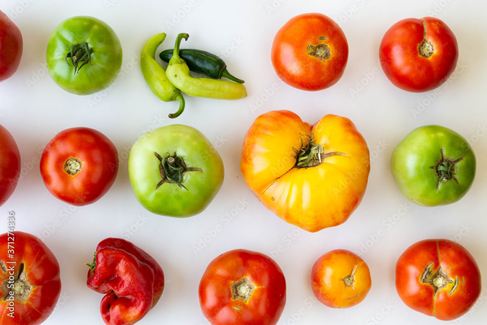 Rows and columns of red and green tomatoes on white background with one of the spaces replaced by peppers. Rows and columns of red and green tomatoes on white background with one of the spaces replaced by peppers.