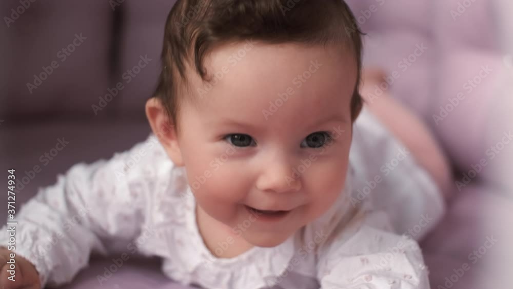 Newborn baby, Care and Love, Portrait of a Child. A newborn female child lies on her stomach in the crib and laughs.