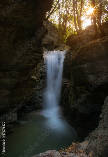 High quality landscape photo for a beautiful natural waterfall cascade during the golden hour afternoon with waters running dreamily through a mountain in Grenoble France at Les Cuves de Sassenage