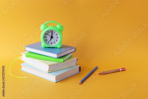 Back to school, stationery, alarm clock, stack of books on bright background, preparation of accessories for learning, at home