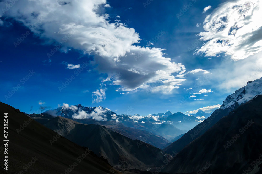 A close up view on high, snow capped Himalayan peaks along Annapurna Circuit in Nepal. Barren and sharp slopes. Mountains are partially shrouded with clouds. Exploration and discovering new places