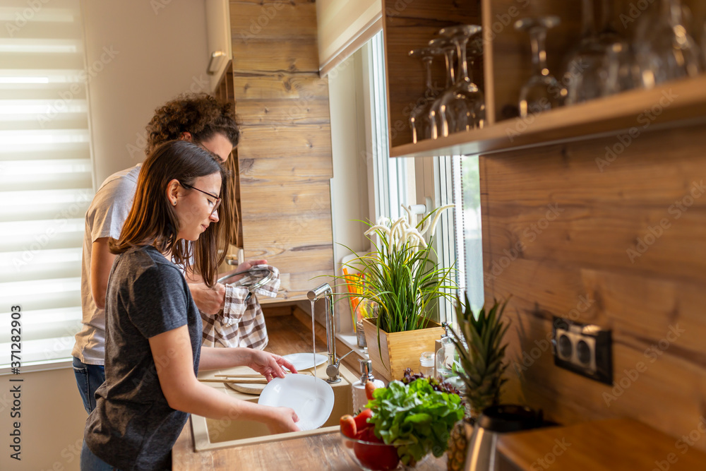 Woman washing the dishes while man is drying them