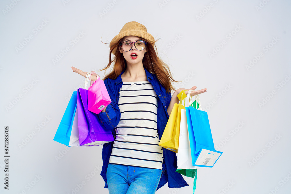 fashionable woman is shopping with packages on a light background in a striped t-shirt, glasses on her face