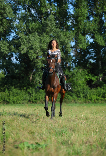 Beautiful young woman riding a horse on the summer field © horsemen