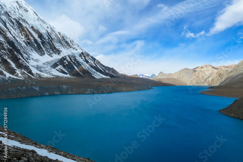 A panoramic view on turquoise colored Tilicho lake in Himalayas, Manang region in Nepal. The world's highest altitude lake (4949m). Snow capped mountains around. Calm surface of the lake. Serenity