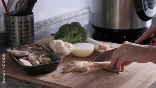 A woman's hands splitting vegetables on a wooden board in the kitchen