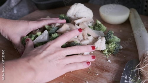 A woman's hands splitting vegetables on a wooden board in the kitchen