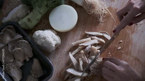 A woman's hands splitting vegetables on a wooden board in the kitchen