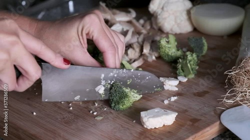A woman's hands splitting vegetables on a wooden board in the kitchen