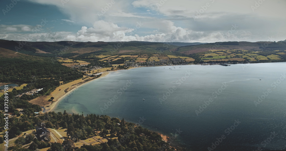 Scotland's ocean, Brodick Harbour aerial view: ferry, ships, boats. Majestic seascape of pier at Firth-of-Clyde Gulf. Nature landscape of wide forests, parks and meadows shot