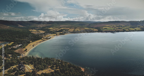 Scotland's ocean, Brodick Harbour aerial view: ferry, ships, boats. Majestic seascape of pier at Firth-of-Clyde Gulf. Nature landscape of wide forests, parks and meadows shot