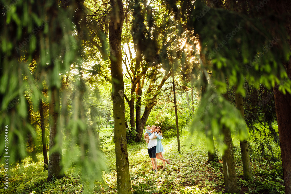 Lovely couple with little daughter walking at the park, caring father hold in arms cute toddler, attractive woman and handsome man hugging, smiling, family moments concept Lovely couple with little daughter walking at the park, caring father hold in arms cute toddler, attractive woman and handsome man hugging, smiling, family moments concept