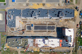 Construction site of an apartment house in a course of building with working tower crane. Aerial view.