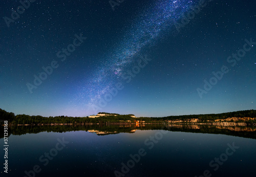 Beautiful landscape of the milky way over the lake. Reflexes of the starry sky in the water.