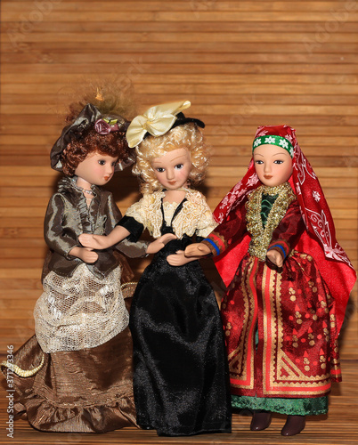 Three dolls in chic outfits on a wooden background.