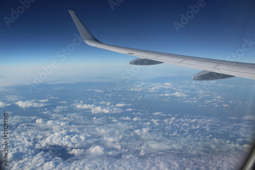 flying over clouds and the sea – looking out of a plane window, the left wing infront