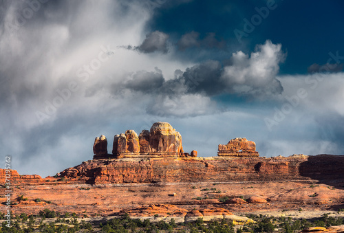 Steep stony red mountain slope under a cloudy sky.