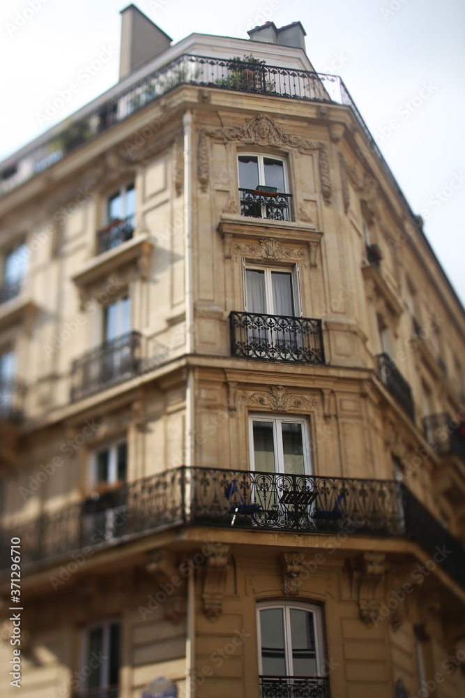 A cute French balcony with flowers under a blue sky. Tilt-shift.