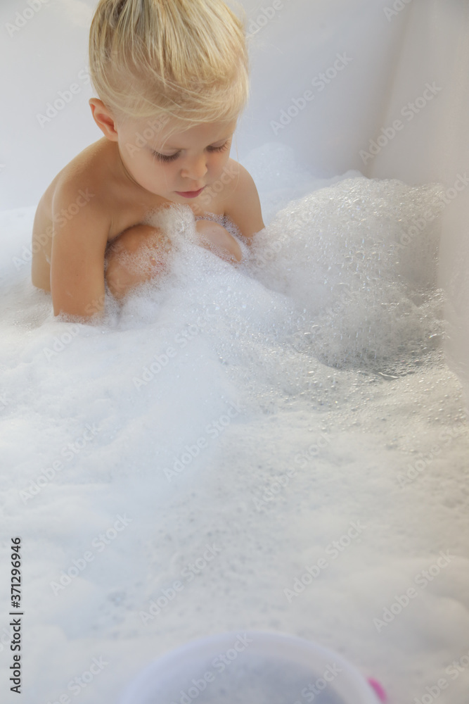 Blonde caucasian toddler girl bathing in a tub full of soap bubbles Blonde caucasian toddler girl bathing in a tub full of soap bubbles