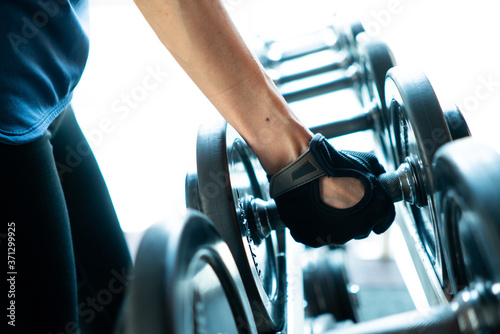 Close-up of a woman takes a dumbbell in the gym preparing to workout for fit and firm