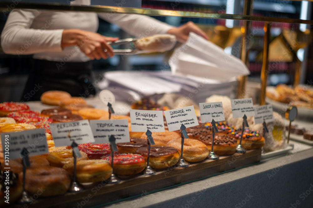 Fresh delicious doughnuts on display in a bakery. Different flavor homemade doughnuts being served at a shop.